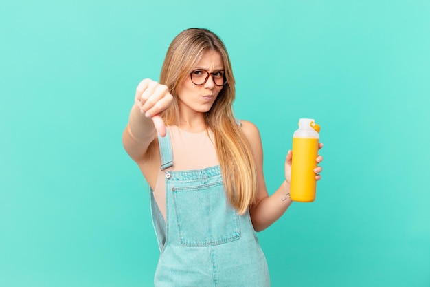 Mujer joven con un sentimiento de batido cruzado, mostrando los pulgares hacia abajo