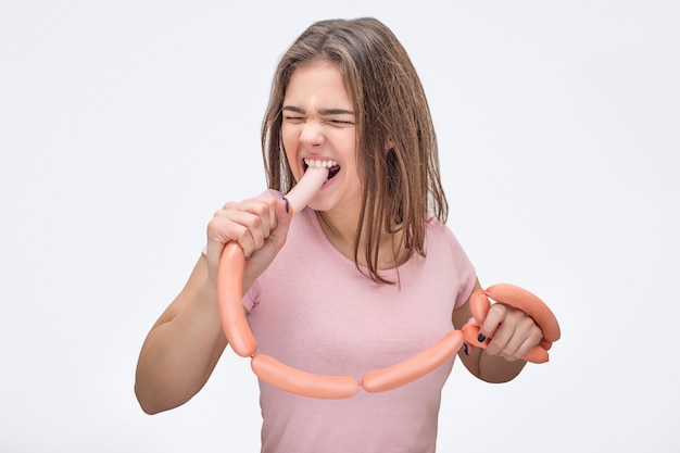 Foto mujer joven seria morder una salchicha