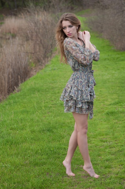 Mujer joven seria de pie sobre la hierba de primavera