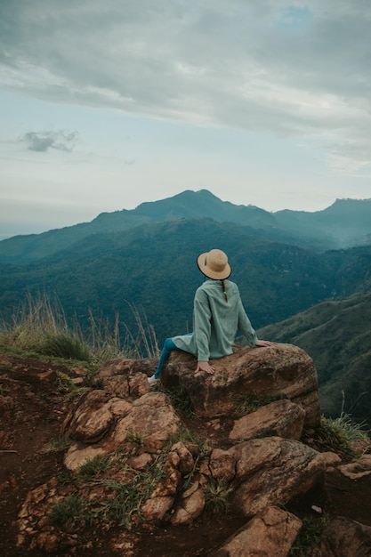 La mujer joven se sienta en el pico del pequeño Adán