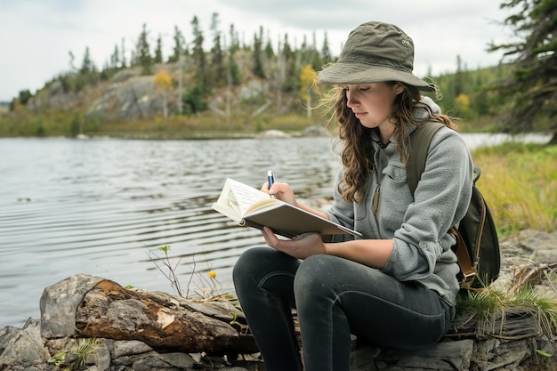 Una mujer joven se sienta bajo un sauce crea versos en un cuaderno desgastado junto a un reflexivo tranquilo