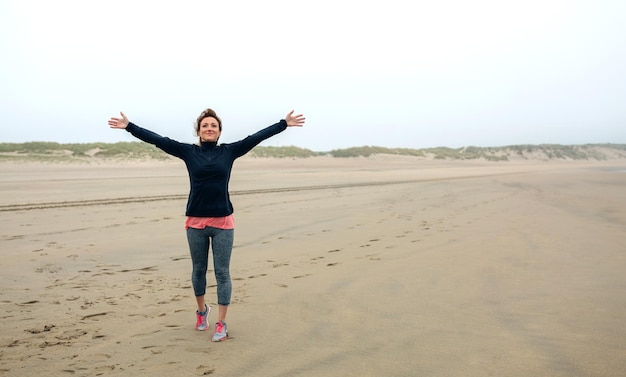 Mujer joven sintiéndose libre en la playa en otoño