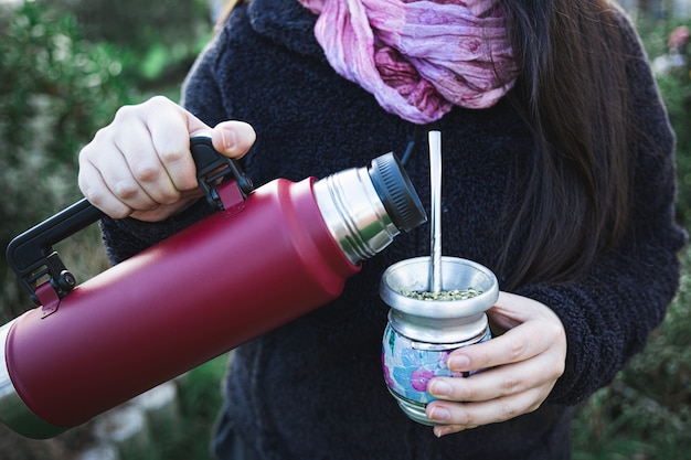 Mujer joven sirviendo mate en un espacio natural bebida latina