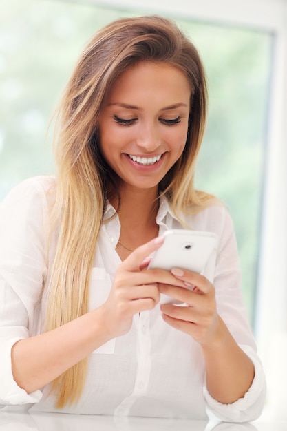 Mujer joven con smartphone en cocina