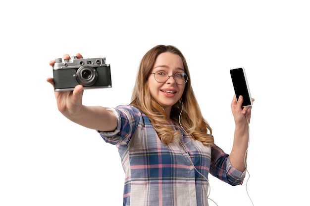 Mujer joven con smartphone, dispositivos, gadgets aislados en la pared blanca del estudio