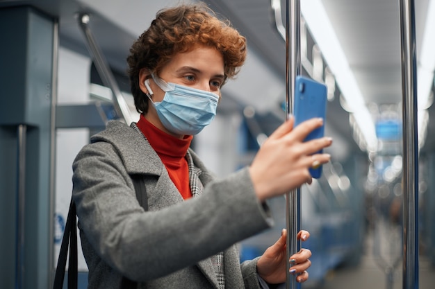 Mujer joven con smartphone durante el viaje en metro