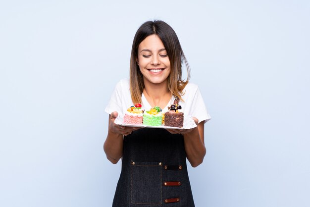 Mujer joven sobre azul aislado con mini tortas