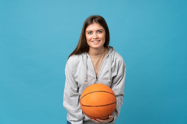 Mujer joven sobre azul aislado con pelota de baloncesto