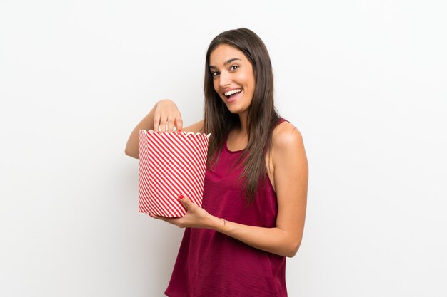 Mujer joven sobre blanco comiendo palomitas de maíz