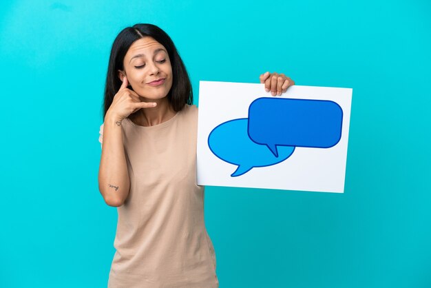 Foto mujer joven sobre fondo aislado sosteniendo un cartel con el icono de la burbuja del discurso y haciendo gesto de teléfono