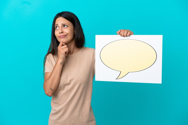 Foto mujer joven sobre fondo aislado sosteniendo un cartel con el icono de la burbuja del discurso y el pensamiento