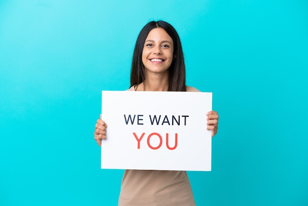 Mujer joven sobre fondo aislado sosteniendo We Want You board con expresión feliz