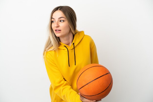 Mujer joven sobre fondo blanco aislado jugando baloncesto