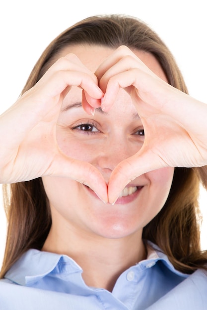 Mujer joven sobre fondo blanco aislado sonriendo enamorada mostrando el símbolo del corazón y la forma con las manos en concepto romántico