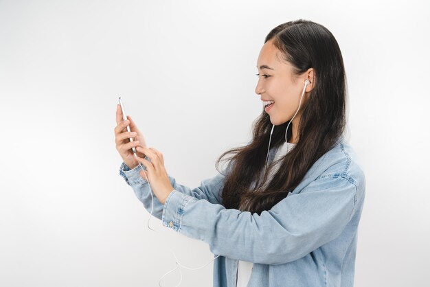 Mujer joven sobre fondo blanco aislado usando móvil con auriculares