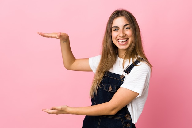 Mujer joven sobre fondo rosa aislado con copyspace para insertar un anuncio