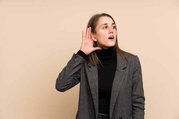 Mujer joven sobre la pared aislada que escucha algo