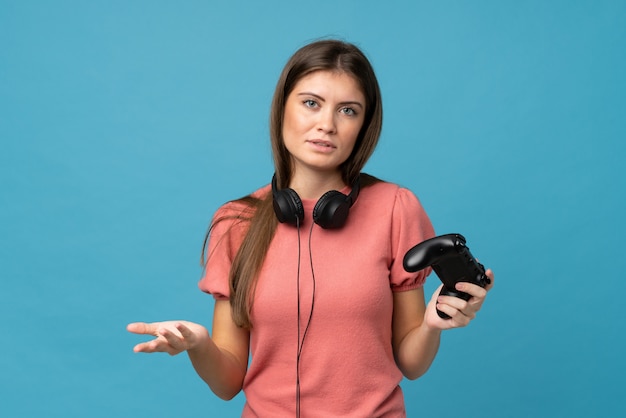 Mujer joven sobre pared azul aislada jugando en videojuegos