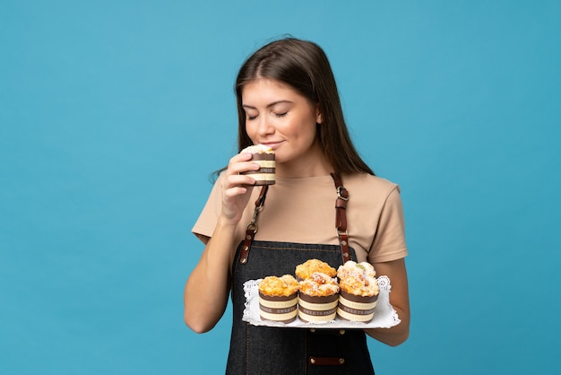 Mujer joven sobre pared azul aislada con mini tortas