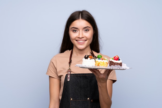 Mujer joven sobre pared azul aislada con mini tortas