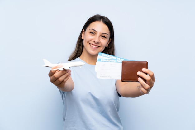 Foto mujer joven sobre pared azul aislada sosteniendo un avión de juguete