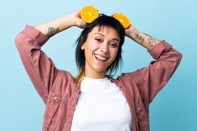 Mujer joven sobre pared azul con una naranja