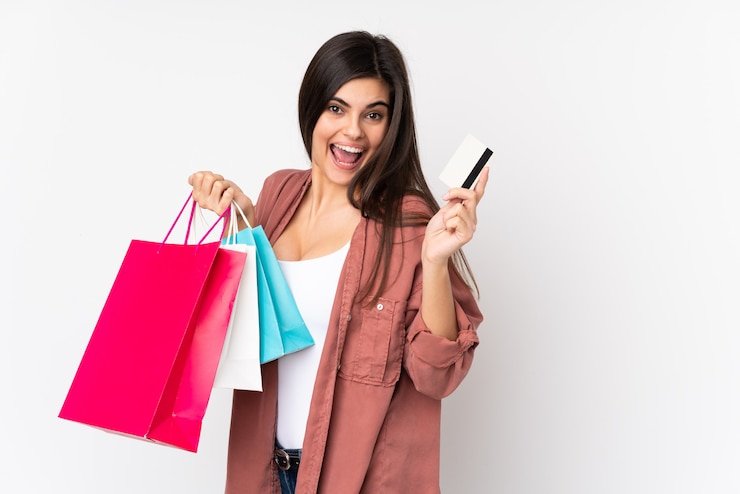 Foto mujer joven sobre pared blanca aislada con bolsas de compras y una tarjeta de crédito