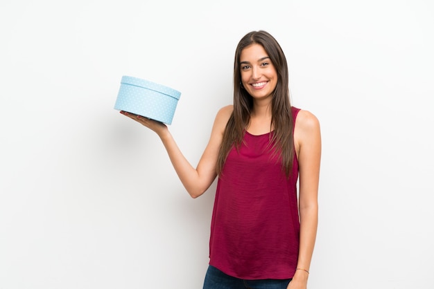 Foto mujer joven sobre pared blanca aislada con caja de regalo