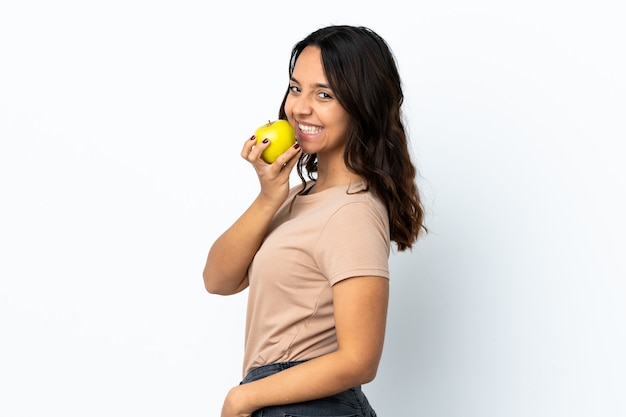 Mujer joven sobre pared blanca aislada comiendo una manzana