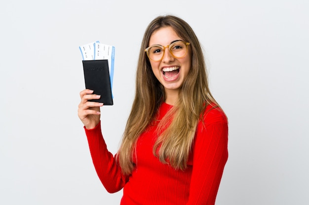 Mujer joven sobre pared blanca aislada feliz de vacaciones con pasaporte y billetes de avión