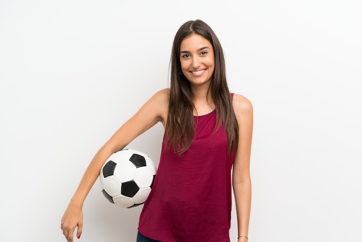 Foto mujer joven sobre pared blanca aislada sosteniendo un balón de fútbol