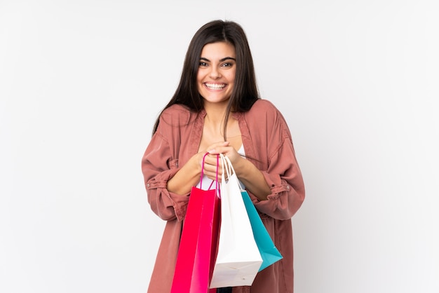 Mujer joven sobre pared blanca con bolsas de compras y sorprendido