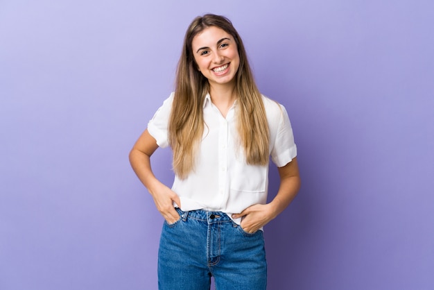 Mujer joven sobre pared púrpura aislada riendo