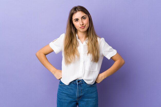 Mujer joven sobre pared púrpura enojada