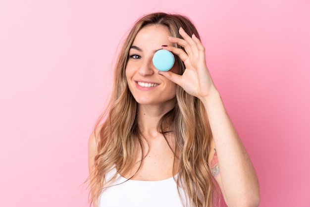 Mujer joven sobre pared rosa aislada con coloridos macarons franceses