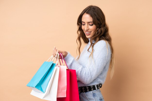 Mujer joven sobre pared sosteniendo bolsas de compras