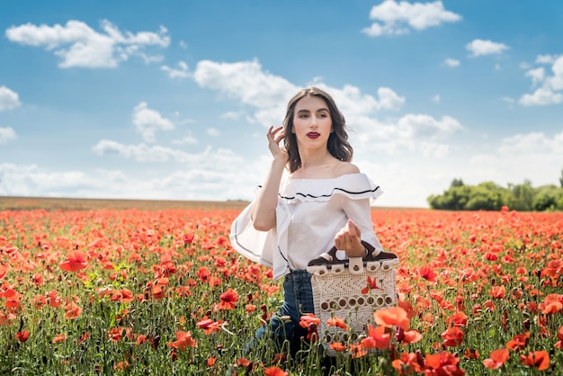 Mujer joven sola en amapola en día de verano de campo, estilo de vida