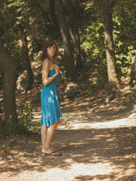 Foto mujer joven en las sombras en un camino en el bosque