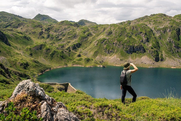 Mujer joven con sombrero admirando las vistas de un lago