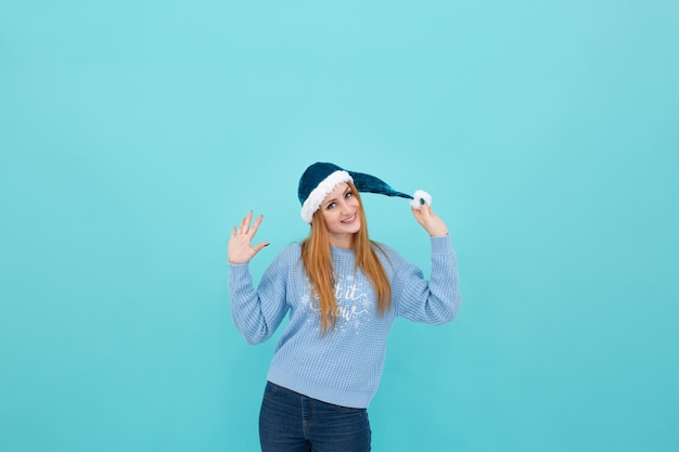 mujer joven en un sombrero de año nuevo sobre un fondo azul. mujer sostiene un sombrero de año nuevo en sus manos. cri