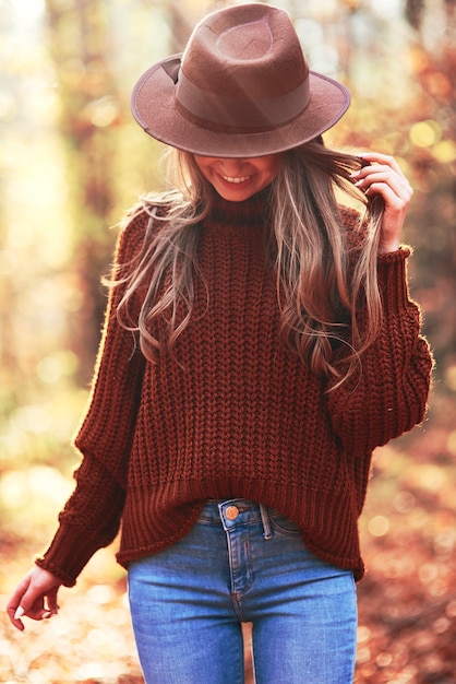 Mujer joven con un sombrero en el bosque de otoño