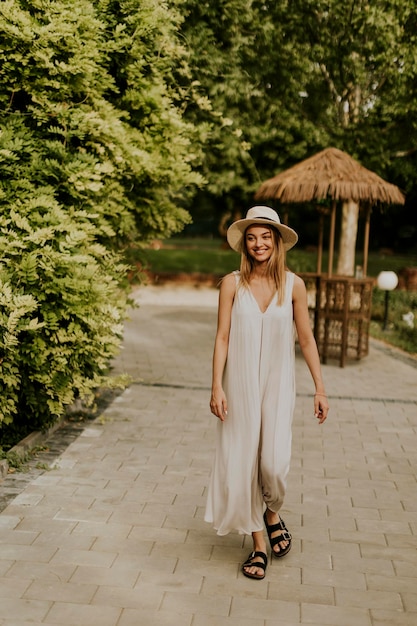 Mujer joven con sombrero caminando en el jardín del resort