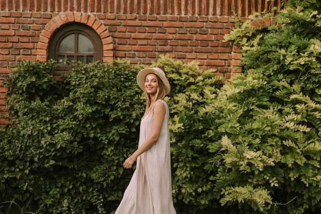 Mujer joven con sombrero caminando en el jardín del resort