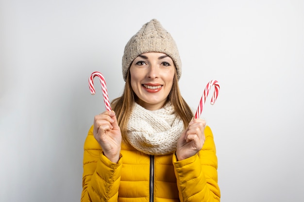 Mujer joven con sombrero y chaqueta tiene bastones de caramelo caramelo