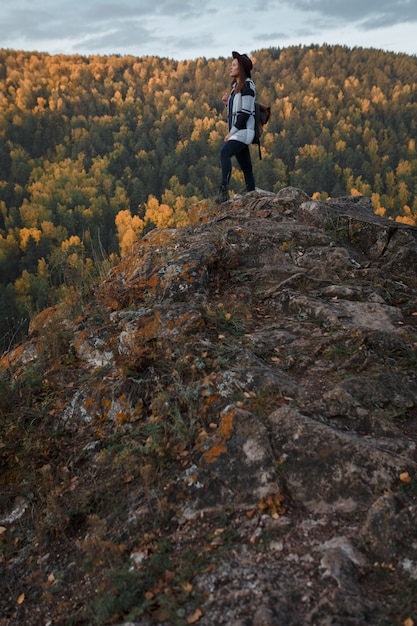 Foto mujer joven con un sombrero en la cima de la montaña