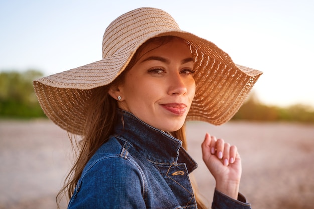 Mujer joven con un sombrero contra el mar azul