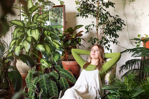 Foto mujer joven con sombrero contra las plantas