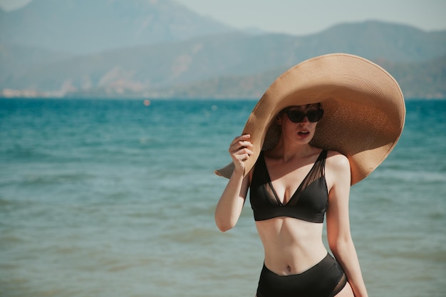 Mujer joven con un sombrero grande en el fondo del mar