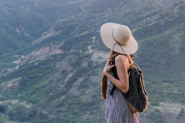 Mujer joven con sombrero grande y mochila en el fondo de la naturaleza Chica viaja un concepto