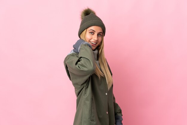 Foto mujer joven con sombrero de invierno aislado en espacio rosa riendo